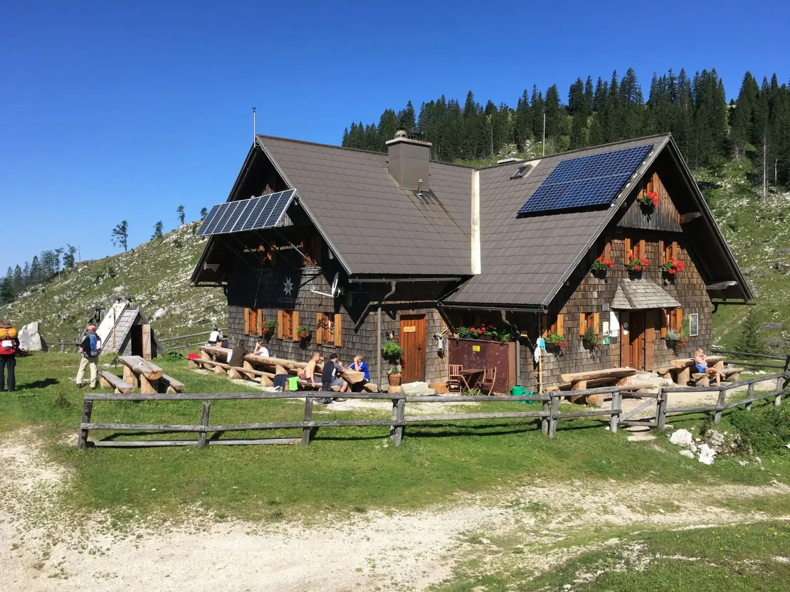 Holzhaus mit Photovoltaikanlage vor Tiroler Bergpanorama